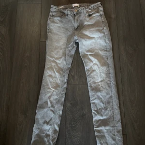 Gråa Jack&Jones Jeans  - Säljer ett par gråa jeans från Jack&Jones. Jeansen har klassisk femficksdesign, knappgylf och raka ben. Materialet är mjukt och stretchigt vilket gör dem bekväma att bära. Perfekt för dig som gillar en stilren look. 