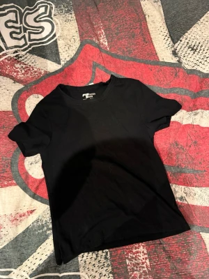 Svart slim fit t-shirt från FB Sister - En klassisk svart t-shirt från FB Sister i slim fit-modell. T-shirten har rund halsringning och korta ärmar, perfekt för en clean och enkel stil. Tillverkad i mjukt material som sitter skönt mot kroppen.
