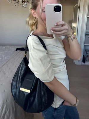 Gucci guccissima hobo bag, black  - Säljer en svart axelväska från Gucci i mjukt läder med diskret GG-mönster och guldfärgad metallbricka framtill. Väskan har en avslappnad, rundad form och bred axelrem för skön komfort. Väskan är äkta och köpt från A Retro Tale, med kommer dust bag också. Finns bevis och serie nummer i väskan 