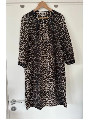 Gerard Darel leopardmönstrad klänning - Ljuvlig leopardmönstrad klänning från Gerard Darel i storlek 40. 100% silke/siden, så bra material som andas. Klänningen har en rund halsringning med en knappstängning framtill och långa ärmar med manschetter. Fina detaljer i svart kontrastfärg runt halsringningen och ärmslut. Klänningen är designad med ett löst fritt fall, perfekt inför vår och sommar. Nypris 2800:-. Mycket gott skick, som ny!