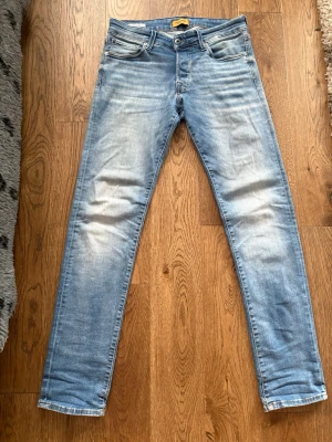 Jack & Jones jeans Slim/Glenn ljusblå  - Snygga ljusblå slim fit jeans från Jack & Jones med klassisk femficksmodell och slitna detaljer på låren. Jeansen har normal midja, dragkedjegylf och är tillverkade i mjuk denim med lite stretch för extra komfort. Modellen heter Slim/glenn. 🤩⭐️ W30 L32. Fri frakt 🚚 (Inga hål eller defekter)⭐️
