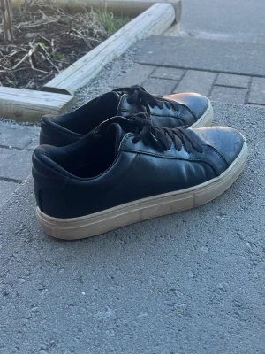 Svarta Vagabond sneakers i läder - Svarta sneakers från Vagabond i stilren design med ovandel i läder och klassisk vit sula. Skorna har svarta skosnören och låg profil, perfekt för en clean och enkel look. Diskret logga på insidan och bekväm passform.