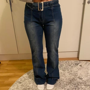 Blå bootcut jeans med hög midja - Dessa jeans har en mörk tvätt med sömmar mitt på låren både fram och bak🙌De har ett bälte som gör de lite roligare🤩OCH självklart så är de förlängda längst ner vilket gör att innerbenslängden hamnar på 94 cm!💙Strl L är en uppskattning så testa mät de måtten som står för att säkerställa att de passar just dig!! Hör av er vid frågor😊