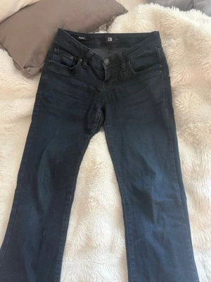 Mörkblå bootcut jeans från LTB - Snygga mörkblå bootcut jeans från LTB med klassisk femficksdesign och subtila slitningar. Jeansen har normal midja och är tillverkade i stretchigt denim för en bekväm passform. Perfekta för en trendig och avslappnad look. 