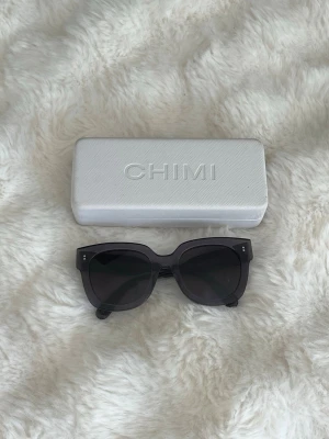 Chimi solglasögon - #008 GINGER  - Snygga gråa solglasögon från Chimi med markerad, fyrkantig båge och mörka glas. Klassisk och trendig design som ger en cool look. Perfekta för att lyfta vilken outfit som helst. Inga defekter vad jag kan hitta förutom att fodralet och posen har några små skavanker!