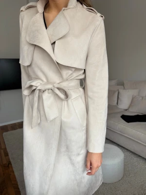 Beige kappa från H&M - Beige kappa i mockaimitation från H&M, lite fläckar som är inringat. Kanske går bort i tvätt.