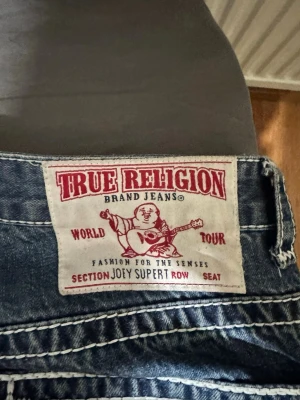 True Religion blå jeans Joey Super T - Säljer ett par blå jeans från True Religion, modell Joey Super T. Säljer den för det var inte riktigt min stil. Har du några frågor skriv till mig. Priset är diskuterabar (har ett litet problem på backfickan) 