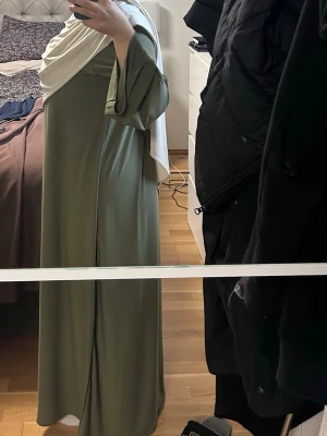 Olivgrön premium jersey abaya  - Säljer en olivgrön  premium jersey abaya enkel, rak passform. Klänningen har en modest stil och är tillverkad i ett mjukt, fallande tyg som ger en snygg siluett. Perfekt till sommaren