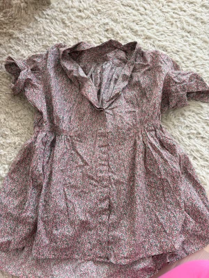 acne jeans blus - Supersöt kortklänning med småblommigt mönster i rosa och grönt på ljus botten. Klänningen har volang vid halsringningen och korta ärmar. Perfekt för vår och sommar!