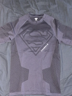 Svart Superman t-shirt från YOUNGLA - Svart t-shirt med Superman-logga i mörkgrått från YOUNGLA. Använd en gång.