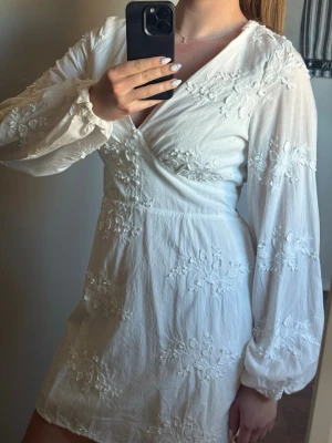 Vit klänning med broderi - Säljer denna superfina vita klänningen med broderade blommor och långa puffigare ärmar🌺 Är i fint skick och kan vara den perfekta studentklänningen! Har varit slutsåld länge