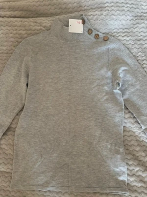 Långärmad tröja med halv polokrage - Fin ljusgrå långärmad tröja med halv polokrage. Fina detaljer vid axeln. Storlek S, aldrig använts. 🌸