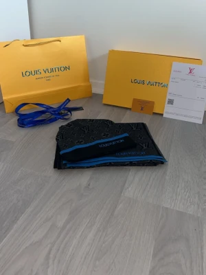 Riktigt snygg blå svart set från H&M - Riktigt snygg och skön halsduk med mössa från H&M. Perfekt för vindar och kalla vädrar.med L mönstrar på från H&M