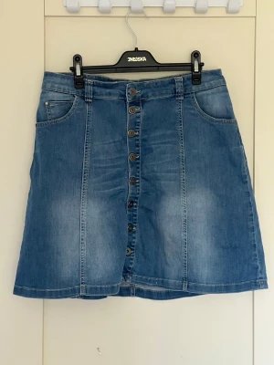 Blå jeanskjol från Rabalder - Snygg blå jeanskjol med knappar hela vägen framtill och fickor på sidorna o bak. 