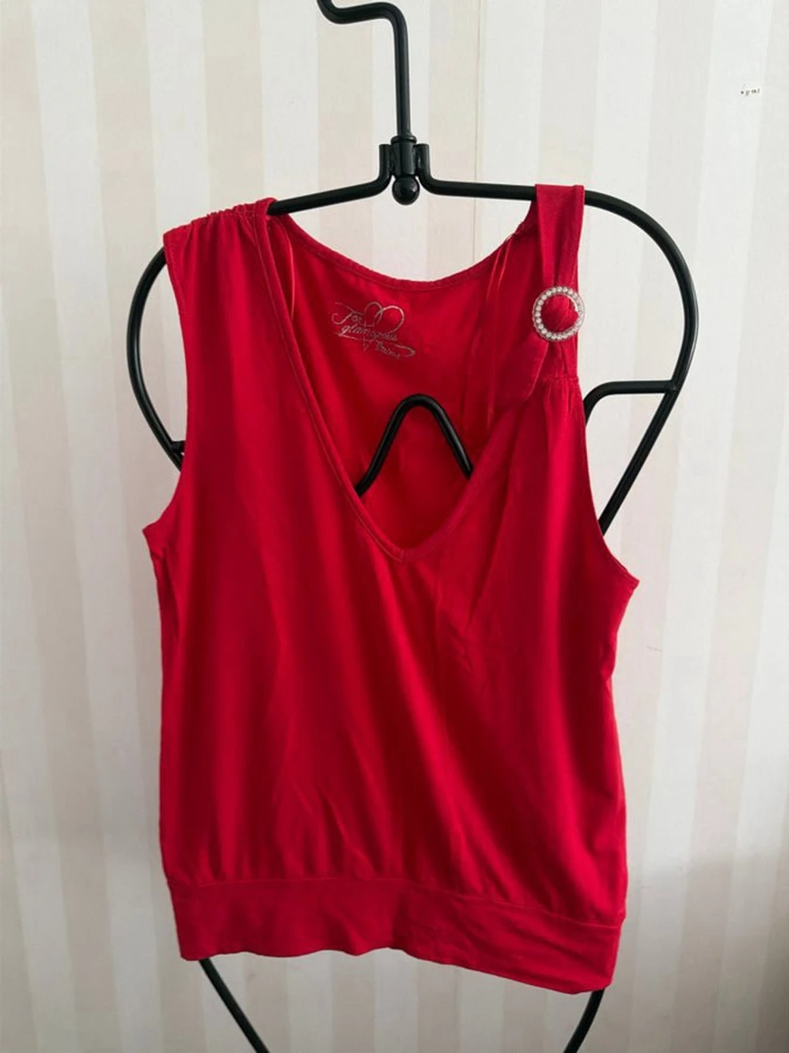 Röd linnetopp med dekorativ brosch