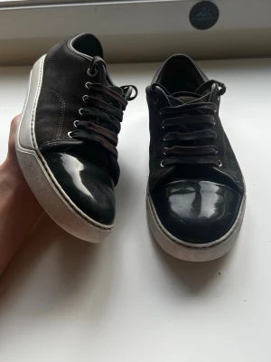 Lanvin skor DBB1 cap toe - Bruna mockaskor med cap toe från Lanvin, modell DBB1, storlek UK 6 (ungefär EU 40–41). Skorna är i bra skick, med två mindre defekter: ett hål på hälarna som inte märks tack vare en tunn extra sula, samt en liten slitning bak på skon som knappt syns. Nypris ligger på 4499 kr. Inga originaltillbehör medföljer.  Kolla gärna in profilen också, där finns flera märkeskläder och skor – du hittar säkert något mer som passar 😉💯 Hör av dig om du undrar något