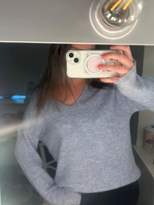 Ljusblå stickad tröja från ONLY - Mysig stickad tröja i ljusblå från ONLY med v-ringning och långa ärmar. Tröjan har en avslappnad passform och ribbstickad struktur som ger en skön och trendig look. Perfekt att matcha med jeans eller kjol för en chill stil.