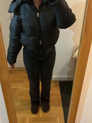 Svart pufferjacka - Weekday - Säljer en svart pufferjacka med huva och dragkedja framtill. Jackan har en boxig passform och bred som. Köpt på Weekday för ca 3 år sedan, knappt använt och inte tillgänglig /online  längre 