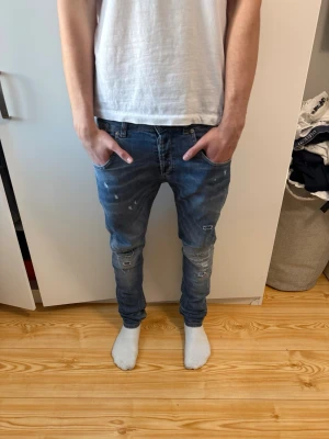 Dondup Jeans - Säljer ett par blå slim fit jeans med slitningar och trasiga detaljer på både fram- och baksida från Dondup, modellen collway men dem sitter som Modellen George, nyskick använd några få gånger inga defekter. Nypris-4000kr mitt pris-899kr. Storlek W31 men kan även passa som W32