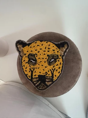 Rund brun handväska med öron - Söt rund plånbok i mjuk brun sammet med små öron upptill. Väskan har en beige ficka med dragkedja på baksidan och detaljer i tyg. Perfekt för dig som gillar gulliga accessoarer och vill sticka ut lite extra.