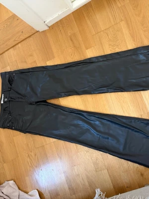 Svarta coated jeans Pull&Bear - Säljer ett par svarta coated jeans från Pull&Bear i storlek 38. 