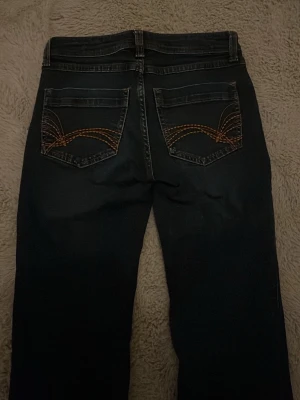 Blåa  jeans från Divided, strl 36 - Säljer ett par blåa bootcut jeans från Divided i storlek 36. Klassisk femficksmodell med snygga kontrastsömmar och broderade detaljer på bakfickorna. Jeansen har dragkedjegylf och knapp med Divided-logga. Perfekta till din vardagsstil! Är ganska gamla men har aldrig använt.