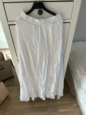 Vit långkjol från Design By Sí - Säljer en luftig och skön vit långkjol. Kjolen har en avslappnad passform med resår i midjan och ett lätt tyg som ger en chill vibe. Perfekt för varma dagar och enkel att matcha med olika toppar. Ej genomskinlig!💗