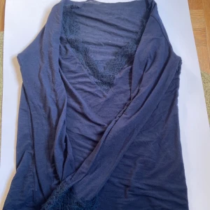 Mörkblått nattlinne med spetsdetaljer - Snyggt mörkblått nattlinne med djup V-ringning och dekorativa spetsdetaljer vid halsringning och ärmslut. Mjukt och tunt material som känns skönt mot huden. Perfekt för mysiga kvällar hemma och utomhus. Har använts. Är storlek L men passar för dig som har mindre. Från Intimissimi. ✨✨✨
