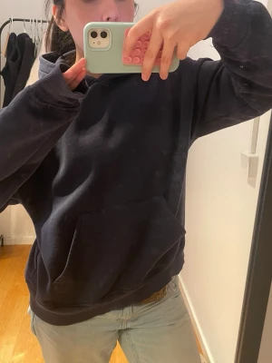 Mörkblå hoodie med magficka - En enkel och stilren mörkblå hoodie med stor magficka och huva. Hoodien har ribbade muddar vid ärmslut och nederkant. Perfekt för en avslappnad look och passar till det mesta. Materialet känns mjukt och bekvämt.