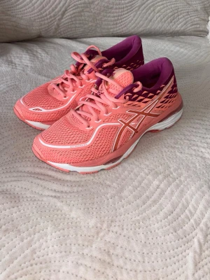 Rosa Asics sneakers med lila detaljer - Snygga sneakers från Asics i en fräsch rosa färg med lila detaljer och vita inslag. Skorna har mesh-överdel för bra ventilation.