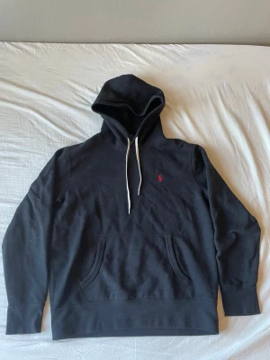 Ralph lauren hoodie - Snygg svart hoodie från Polo Ralph Lauren med huva. Tröjan har snörning vid huvan och en liten röd logga broderad på bröstet. Perfekt för chill dagar och enkel att matcha med jeans eller mjukisbyxor. Storlek M men passar även bra som S. Skick 9/10 möjligen en och annan tråd som är lös annars är skicket galant. Kom gärna med frågor och funderingar!!