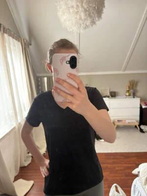 Svart tränings T-shirt - En enkel svart t-shirt med v-ringad hals och korta ärmar. T-shirten har en normal passform och är tillverkad i mjukt bomullstyg.