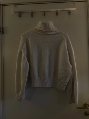 Beige polotröja i stickat material - Mysig beige stickad polotröja med bred ribbad krage, muddar och nederkant. Tröjan har en avslappnad passform och långa ärmar, perfekt för lager-på-lager-stil. Materialet ser ut att vara mjukt och värmande, idealiskt för kyliga dagar.Hör av dig om du har några frågor! 💗🫶🏼