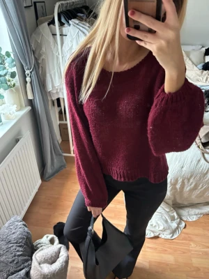 Vinröd stickad tröja - Mysig vinröd stickad tröja med rund halsringning. Tröjan har en avslappnad passform och ribbade muddar vid ärmslut och nederkant. Perfekt för kalla dagar och enkel att styla till olika outfits.