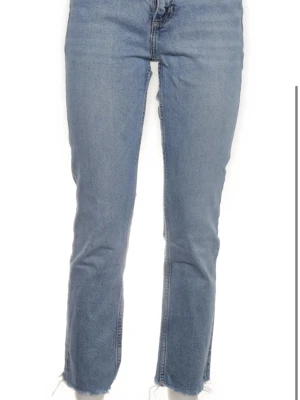 Zara jeans  - Säljer ett par ljusblå raka jeans med hög midja och råa, fransiga benslut. Klassisk femficksmodell i denimtyg. Perfekta till sneakers eller boots för en avslappnad look. Storlek 38 i nyskick 