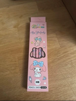 My Melody rosa blyertspennor - Säljer ett set med 12 rosa blyertspennor med My Melody-motiv. Pennorna har söta tryck med figurer och detaljer i blått och vitt. Förpackningen är också dekorerad med My Melody och andra gulliga illustrationer. Perfekt för dig som gillar kawaii-stil.