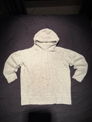 Ljusgrå stickad hoodie - En stilren ljusgrå hoodie med huva och dragsnören. Perfekt för en avslappnad look. Pris kan diskuteras