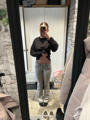 Gråa bootcut jeans med fickor - Säljer ett par gråa bootcut jeans med snygga fickor bak och dekorativa knappar. Jeansen har låg midja och klassisk femficksdesign. 