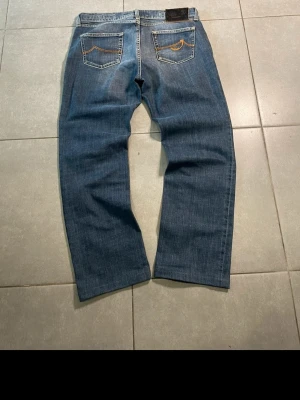 Jacob Cohen jeans - Säljer ett par klassiska blåa jeans från Jacob Cohen med raka ben och snygga kontrastsömmar på bakfickorna. Jeansen har fem fickor och är tillverkade i denim med en cool tvätt. Perfekta för en avslappnad stil. Observera att dem är upplagda på bild. Jag har tagit bort sömmarna så de är sin ursprungliga längd.