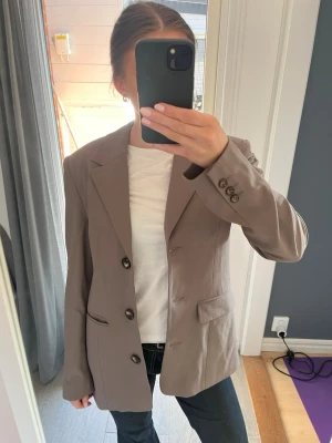 Beige oversized kavaj   - Säljer en beige brun oversized kavaj med klassiska slag och tre mörka knappar framtill. Kavajen har två fickor och är i ny skick  🌷