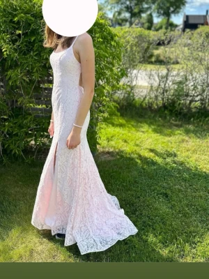 Ljusrosa balklänning  - Säljer nu min  ljusrosa balklänning med öppen rygg och spets över hela klänningen. Klänningen har smala axelband och en lätt slits framtill. Materialet är spets med små paljetter/stenar upptill på klänningen. Klänningen har vadderade kupor. Klänningen är endast använd vid ett tillfälle och är därför i väldigt fint skick. Man kan endast se tecken på användning om man tittar noga på undersidan av släpet av klänningen men det syns absolut inte när man har klänningen på sig. Köpt för 2200kr.