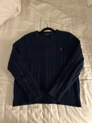 Mörkblå kabelstickad tröja Polo Ralph Lauren - Stickad ralph lauren tröja i marinblå. Har används en del men är frf fräsch därav pris.