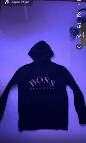  Hugo Boss hoddie  - Svart hoodie från Hugo Boss med stor BOSS-logga i vitt på bröstet. Tröjan har huva med snörning och långa ärmar. Mjuk och skön, perfekt för chill dagar. Klassisk och stilren design som funkar till det mesta.