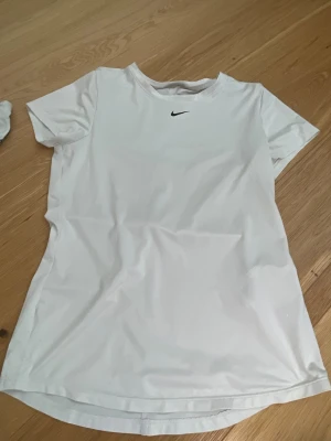 Vit Nike t-shirt  - Säljer en vit sport t-shirt från Nike med klassisk svart logga på bröstet.