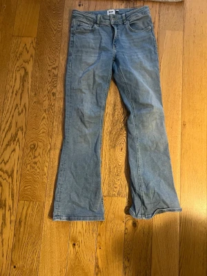 Ljusblå bootcut jeans från 157 - Säljer ett par ljusblå bootcut jeans från 157 med klassisk femficksdesign och dragkedja. Jeansen har en avslappnad passform med lätt utsvängda ben och är tillverkade i denim. Perfekta för en trendig och avslappnad stil.
