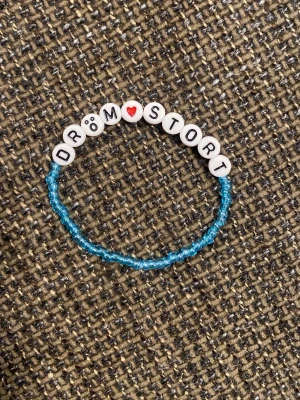 Blått pärlarmband med text - Unikt armband med små blå pärlor och vita bokstavspärlor som stavar 'DRÖM STORT', där O är ett hjärta. Perfekt för dig som gillar personliga accessoarer och vill ha ett peppande budskap på handleden.