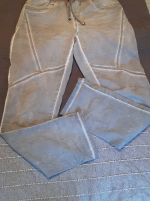 Grå jeans-leggings med dragsko från Bonprix  - Säljer ett par grå jeans- leggings med dragsko i midjan och synliga sömmar längs benen. Byxorna har avslappnad passform och raka ben, perfekta för chill dagar. Materialet känns mjukt och bekvämt, troligen bomull eller bomullsblandning. I tror det är storlek 44/46/XL, után storlek label,  men mått på bilderna. 