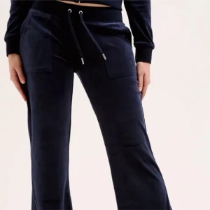 Mörkblå velourbyxor Juicy Couture - Mörkblå mjukisbyxor från Juicy Couture. Byxorna är väl underhållna. Tvättat de enligt instruktionerna, Endast tvättade 2 gånger och har bara användt hemma som mjukisbyxor ett fåtal gånger, ish 5 gånger.