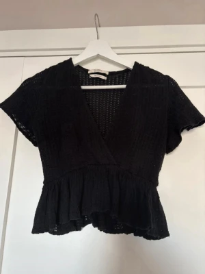 Svart topp med volang - Svart topp med kort ärm och volang nertill. Nyskick!