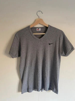 Grå ribbad t-shirt från Nike - Säljer en grå ribbad t-shirt från Nike med v-ringning och korta ärmar. Så snygg och bra basic.